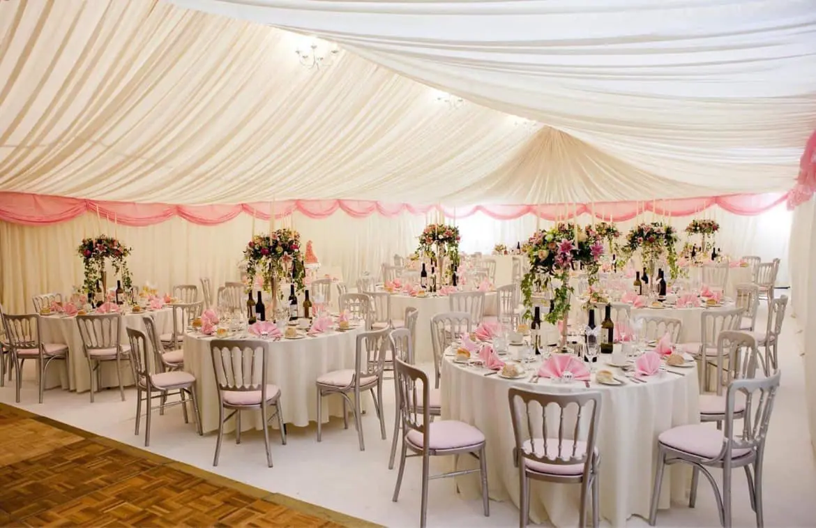 The Main Hall beautifully transformed for a formal wedding reception with an elegant white marquee-style ceiling lining and decorated round tables.